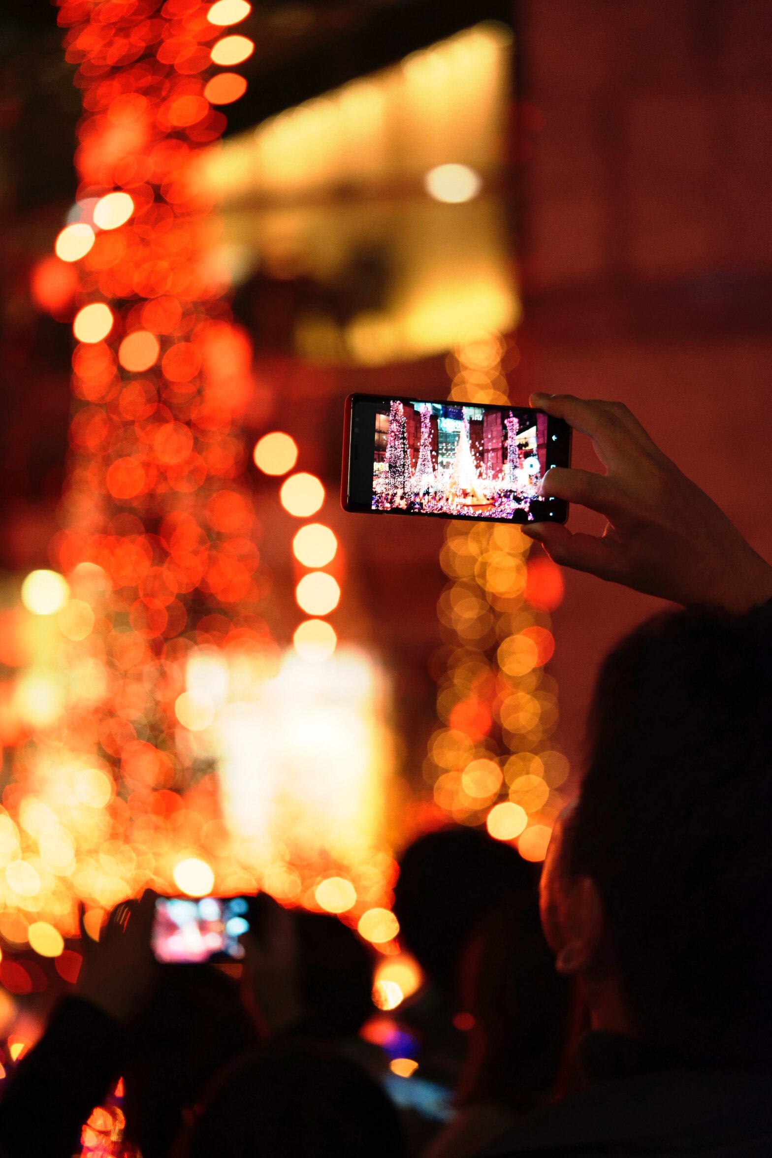 person taking photo of Christmas lights with mobile phone
